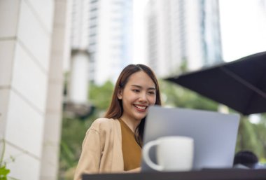 Asyalı kadın yönetici bir kahve dükkanında bulunurken kapsamlı bir analiz yaparak olası bir yatırım projesi için uzaktan onay verdi. Genişleme için dikkatlice tasarlanmış stratejik karar.