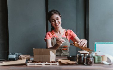 Küçük bir kafe sahibi sürdürülebilir dairesel ekonomiyi teşvik ediyor, toplama, paketleme, kahve çekirdekleri siparişlerini etiketleme, atıkları azaltma ve çevre dostu çevrimiçi alışveriş için geri dönüşümlü materyallerle nakliye.