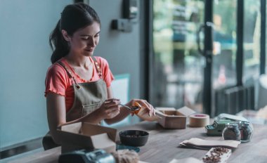 Küçük bir kafe sahibi sürdürülebilir dairesel ekonomiyi teşvik ediyor, toplama, paketleme, kahve çekirdekleri siparişlerini etiketleme, atıkları azaltma ve çevre dostu çevrimiçi alışveriş için geri dönüşümlü materyallerle nakliye.