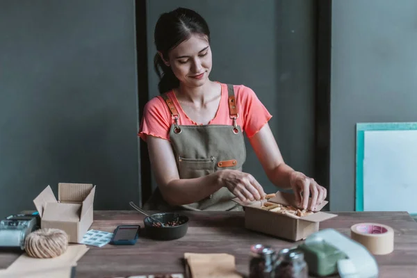 A small cafe owner promotes the sustainable circular economy, picking, wrapping, labeling coffee bean orders , reducing waste, and shipping with recycled materials for eco-friendly online shopping.