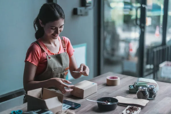 A small cafe owner promotes the sustainable circular economy, picking, wrapping, labeling coffee bean orders , reducing waste, and shipping with recycled materials for eco-friendly online shopping.
