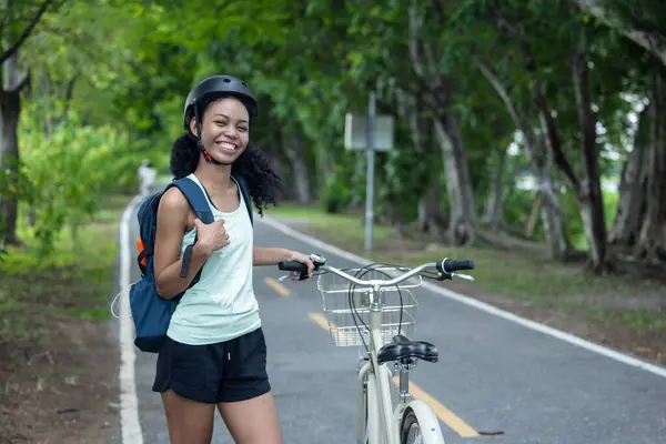 Female cyclist combine eco-consciousness with active lifestyle, using bikes for workout and travel, a portable solar panel for device charging, and embracing recycling practices for circular economy.