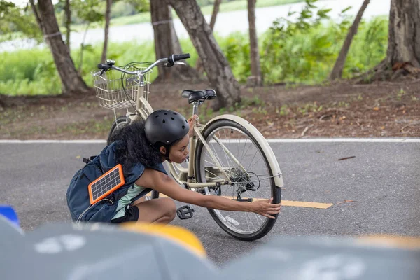 Female cyclist combine eco-consciousness with active lifestyle, using bikes for workout and travel, a portable solar panel for device charging, and embracing recycling practices for circular economy.