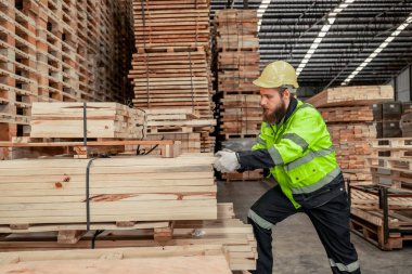 Ölçmek ve doğru boyutu hesaplamak için iştaşlarını seçerken ve taşırken saptanmış bir odun çevirici atışı. kesme, şekil verme, döndürme, pürüzsüz, ahşap fiksasyonları gereksinimlere göre dengelemek için el ve güç araçları kullanarak