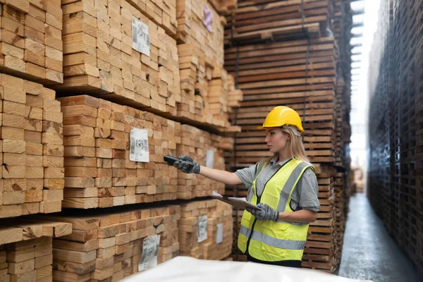 木材パレット倉庫のロジスティクスワーカーは ソフトウェア バーコードスキャナ ノートを含む商品の流れを管理する技術的なツールを使用して 正確にラベルを付ける 工場の倉庫で製品を検証します — ストック写真