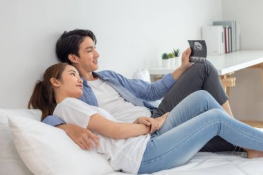 Asyalı çiftler ultrason görüntülerini tararken hamileliğin coşkusunu ve heyecanını kucaklarlar. Bebeğin rahmindeki sağlık, cinsiyet ve gelişimi ortaya çıkar. Mutluluk ve memnuniyet aile içinde bağı güçlendirir.