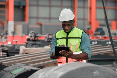 Metal levha işçileri kaliteyi hassasiyetle izlemekte, dijital tabletleri belge ve sertifika için kullanmakta, endüstriyel çatı ve altyapı projelerinde çevre güvencesini artırmaktadır..