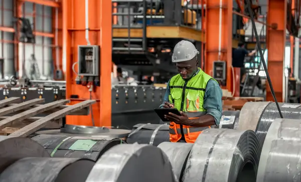 Metal sheet workers monitoring quality with precision, using digital tablets for documentation and certification, improving environmental assurance in industrial roofing and infrastructure projects.