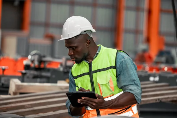 Metal sheet workers monitoring quality with precision, using digital tablets for documentation and certification, improving environmental assurance in industrial roofing and infrastructure projects.