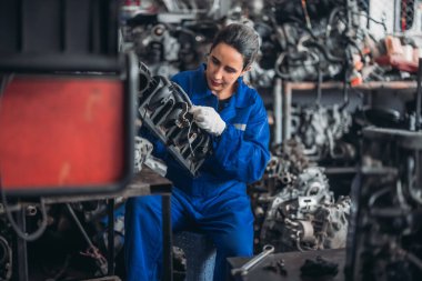 Araba servisi teknisyenleri depodaki motor parçalarını inceliyor, inceliyor. Hassas onarımlar, modifikasyonlar ve montaj için kaliteli dişlileri ve aletleri dikkatlice seçiyor. En uygun araç performansı sağlanıyor