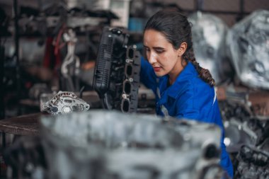 Araba servisi teknisyenleri depodaki motor parçalarını inceliyor, inceliyor. Hassas onarımlar, modifikasyonlar ve montaj için kaliteli dişlileri ve aletleri dikkatlice seçiyor. En uygun araç performansı sağlanıyor