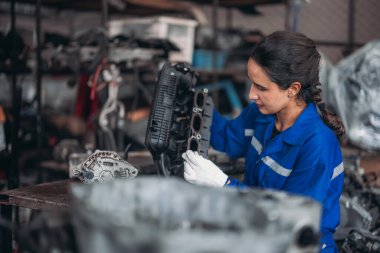 Araba servisi teknisyenleri depodaki motor parçalarını inceliyor, inceliyor. Hassas onarımlar, modifikasyonlar ve montaj için kaliteli dişlileri ve aletleri dikkatlice seçiyor. En uygun araç performansı sağlanıyor