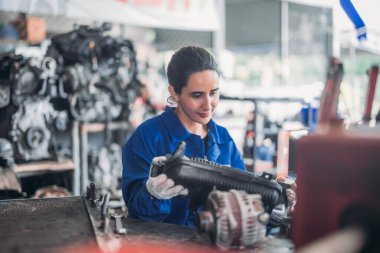 Araba servisi teknisyenleri depodaki motor parçalarını inceliyor, inceliyor. Hassas onarımlar, modifikasyonlar ve montaj için kaliteli dişlileri ve aletleri dikkatlice seçiyor. En uygun araç performansı sağlanıyor