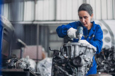 Araba servisi teknisyenleri depodaki motor parçalarını inceliyor, inceliyor. Hassas onarımlar, modifikasyonlar ve montaj için kaliteli dişlileri ve aletleri dikkatlice seçiyor. En uygun araç performansı sağlanıyor