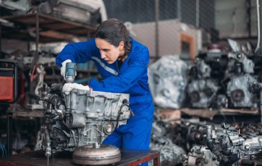 Araba servisi teknisyenleri depodaki motor parçalarını inceliyor, inceliyor. Hassas onarımlar, modifikasyonlar ve montaj için kaliteli dişlileri ve aletleri dikkatlice seçiyor. En uygun araç performansı sağlanıyor