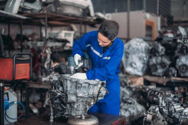 Araba servisi teknisyenleri depodaki motor parçalarını inceliyor, inceliyor. Hassas onarımlar, modifikasyonlar ve montaj için kaliteli dişlileri ve aletleri dikkatlice seçiyor. En uygun araç performansı sağlanıyor