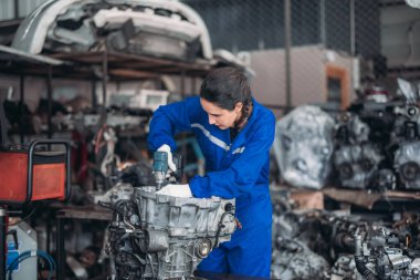 Araba servisi teknisyenleri depodaki motor parçalarını inceliyor, inceliyor. Hassas onarımlar, modifikasyonlar ve montaj için kaliteli dişlileri ve aletleri dikkatlice seçiyor. En uygun araç performansı sağlanıyor