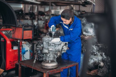 Araba servisi teknisyenleri depodaki motor parçalarını inceliyor, inceliyor. Hassas onarımlar, modifikasyonlar ve montaj için kaliteli dişlileri ve aletleri dikkatlice seçiyor. En uygun araç performansı sağlanıyor