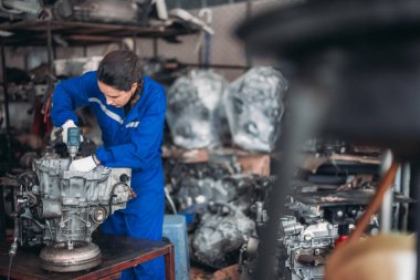 Araba servisi teknisyenleri depodaki motor parçalarını inceliyor, inceliyor. Hassas onarımlar, modifikasyonlar ve montaj için kaliteli dişlileri ve aletleri dikkatlice seçiyor. En uygun araç performansı sağlanıyor