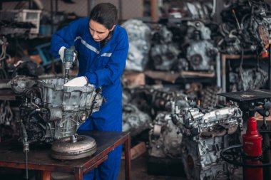 Araba servisi teknisyenleri depodaki motor parçalarını inceliyor, inceliyor. Hassas onarımlar, modifikasyonlar ve montaj için kaliteli dişlileri ve aletleri dikkatlice seçiyor. En uygun araç performansı sağlanıyor