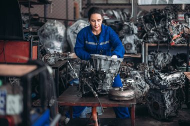 Araba servisi teknisyenleri depodaki motor parçalarını inceliyor, inceliyor. Hassas onarımlar, modifikasyonlar ve montaj için kaliteli dişlileri ve aletleri dikkatlice seçiyor. En uygun araç performansı sağlanıyor