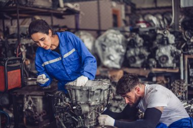 Araba servisi teknisyenleri depodaki motor parçalarını inceliyor, inceliyor. Hassas onarımlar, modifikasyonlar ve montaj için kaliteli dişlileri ve aletleri dikkatlice seçiyor. En uygun araç performansı sağlanıyor