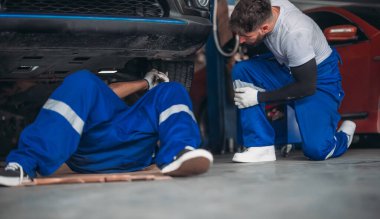 Araba servisi teknisyenleri garajdaki süspansiyon sistemi sorunlarını inceliyor, analiz ediyor ve hassas aletlerle teşhis ediyor. Tespit, sorun giderme, tamir problemleri. En uygun araç performansı ve güvenliği sağlanıyor.