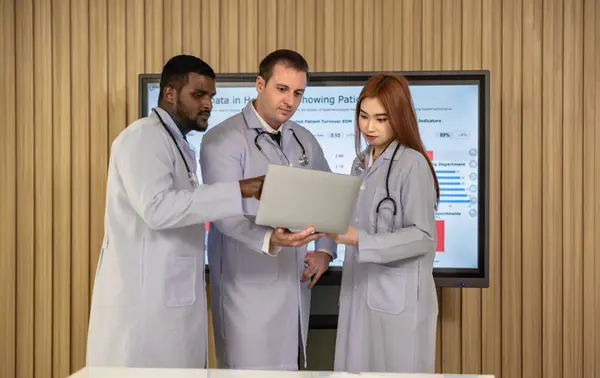 Team of doctors discuss healthcare big data to analyze patient satisfaction trends, waiting status, turnover rates aiming to identify areas for improvement, create cost effective management plans.