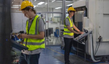 Robotik stajyerler, bir robotik eğitim akademisinin kontrol odasındaki makine monitörleri üzerindeki uygulamalı dersler ve gösteriler yoluyla çalışma, programlama ve sorun çözme tekniklerini öğrenirler..