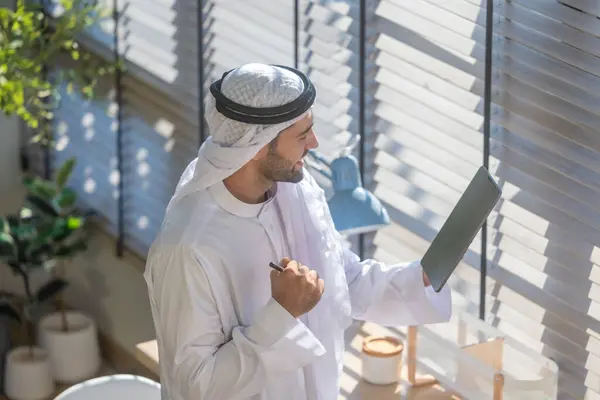 Sheikh, CEO in arb dress, supervising business, distant meetings, and communication via video call with the team with a smile gesture. Overseeing operations as a leader, showcasing responsibilities.