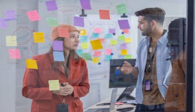 Çok kültürlü bir başlangıç ekibinin beyin fırtınası, fikir alışverişi, yapışkan notlar kullanarak yeni bir bakış açısı. Bir takım olarak çalışmak, şirket için yenilikçi bir fikir, potansiyel bir çözüm oluşturmaya yardımcı olur.