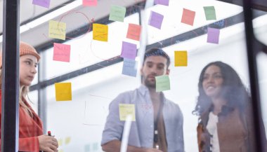 Çok kültürlü bir başlangıç ekibinin beyin fırtınası, fikir alışverişi, yapışkan notlar kullanarak yeni bir bakış açısı. Bir takım olarak çalışmak, şirket için yenilikçi bir fikir, potansiyel bir çözüm oluşturmaya yardımcı olur.