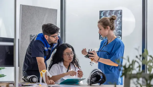 机器人康复工程师与一名骨科医生和一名外科医生合作 为需要先进假肢或康复支持的病人制造体感机器人手臂和手 — 图库照片