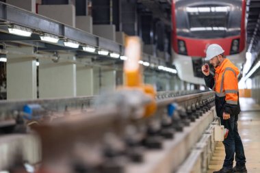 Demiryolu bakım mühendisi altyapının durumunu değerlendiriyor. Karbondioksit ayak izini azaltan, enerji verimliliğini arttıran, sürdürülebilir uygulamalara odaklanan demiryolu sistemine güncellemeler planlamak ve uygulamak