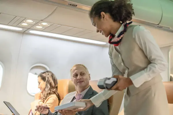 Een Vrouwelijke Stewardess Helpt Zakenreizigers Met Transacties Tijdens Een Vlucht — Stockfoto