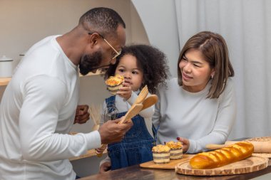 Üç kişilik bir aile, bir baba, bir anne ve bir kız, evde ekmek pişirmekten ve paylaşmaktan zevk alıyorlar..