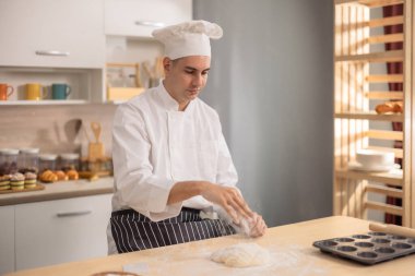 Profesyonel usta aşçı, ticari bir mutfakta ekmek yapmanın ilk aşamalarında un yüzeyinde yoğurur. Yemek için gösteri becerileri, teknik, hassasiyet, tutku ve sanatsallık.