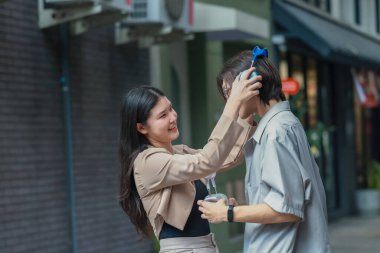 Asyalı aşıklar dışarıda eğlenceli etkileşimlere girerler. Gözleri sevgi dolu bakışlarla buluşur, sevgi ve şefkat saçar. Gülen ve samimi anlar paylaşan İçtenlik ve neşe dolu.