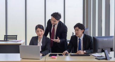 Bir grup iş adamı ofiste iş birliği yapıyor. Biri bilgisayar ekranına işaret ederken, diğerleri dikkatli bir şekilde, takım çalışmasını ve modern iş yerinde etkili iletişimi vurguluyor.