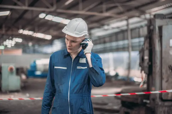 stock image A safety inspector uses a walkie talkie to report an oil leak in an industrial setting. The image captures the critical moment of ensuring safety in a cluttered and potentially hazardous environment.