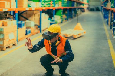 Modern depo ortamında dijital arayüzle etkileşime geçmek için sanal gerçeklik gözlüğü takan bir depo çalışanı. Gelişmiş teknolojinin lojistik ve envanter yönetimine entegrasyonu.