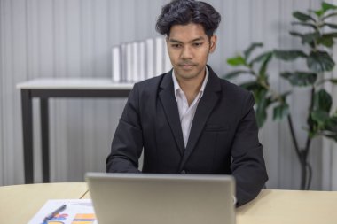 Takım elbiseli profesyonel iş adamı, modern bir ofiste dizüstü bilgisayara çok önem verir. Kurumsal iş ortamları ve iş karar verme senaryoları için konsantrasyon ve ciddiyet.
