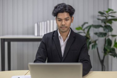 Takım elbiseli profesyonel iş adamı, modern bir ofiste dizüstü bilgisayara çok önem verir. Kurumsal iş ortamları ve iş karar verme senaryoları için konsantrasyon ve ciddiyet.