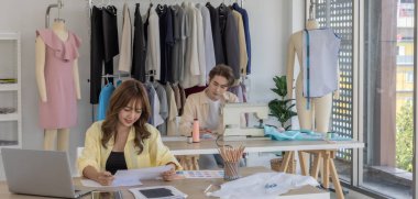 Moda tasarımcısı stüdyoda yeni kıyafet koleksiyonu için renk seçmeye odaklanmış durumda. Çalışma alanı yaratıcı araçlar, kumaş örnekleri, dikiş makinesi, canlı moda tasarım süreci ile dolu.