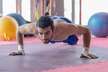 Kendini adamış boksör, spor salonunda güçlü ve disiplinli hareketler sergiliyor. Görüntü sporcunun kas yapısını ve odaklanmış kararlılığını yakalar, eğitim ortamını vurgular