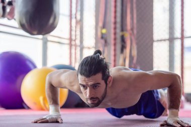 Kendini adamış boksör, spor salonunda güçlü ve disiplinli hareketler sergiliyor. Görüntü sporcunun kas yapısını ve odaklanmış kararlılığını yakalar, eğitim ortamını vurgular