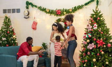 Siyah bir ailenin dans edişinin ve Noel partisinde hediye alışverişinin neşeli ve iç açıcı bir sahnesi, şenlikli dekorasyonlarla çevrili. Aile toplantısının keyifli anları.