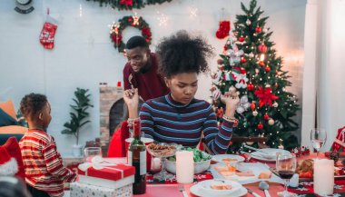 Siyah ailenin Noel yemeğinin keyfini çıkardığı canlı bir sahne, Noel mevsiminin sıcaklığını ve neşesini, güzel dekore edilmiş masaların etrafında yakalıyor, anne, baba ve oğulun özel anlarını paylaştığı.