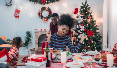 Siyah ailenin Noel yemeğinin keyfini çıkardığı canlı bir sahne, Noel mevsiminin sıcaklığını ve neşesini, güzel dekore edilmiş masaların etrafında yakalıyor, anne, baba ve oğulun özel anlarını paylaştığı.