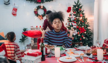 Siyah ailenin Noel yemeğinin keyfini çıkardığı canlı bir sahne, Noel mevsiminin sıcaklığını ve neşesini, güzel dekore edilmiş masaların etrafında yakalıyor, anne, baba ve oğulun özel anlarını paylaştığı.